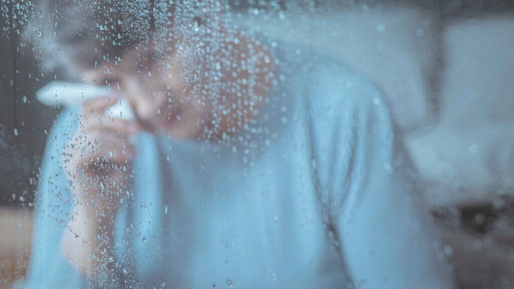 Anziana che piange alla finestra con il maltempo