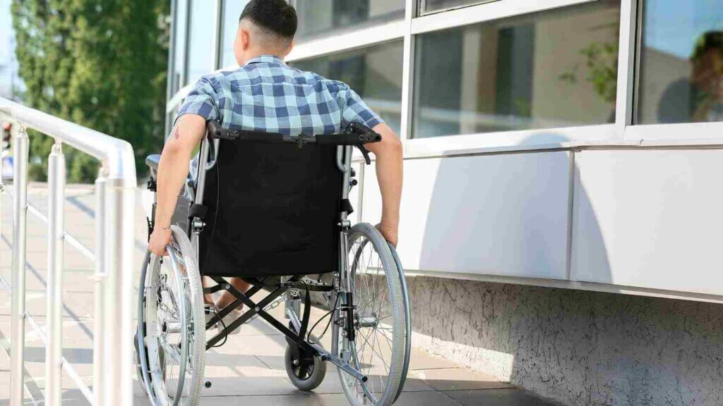 Ragazzo in sedia a rotelle si sposta in autonomia percorrendo una rampa di accesso