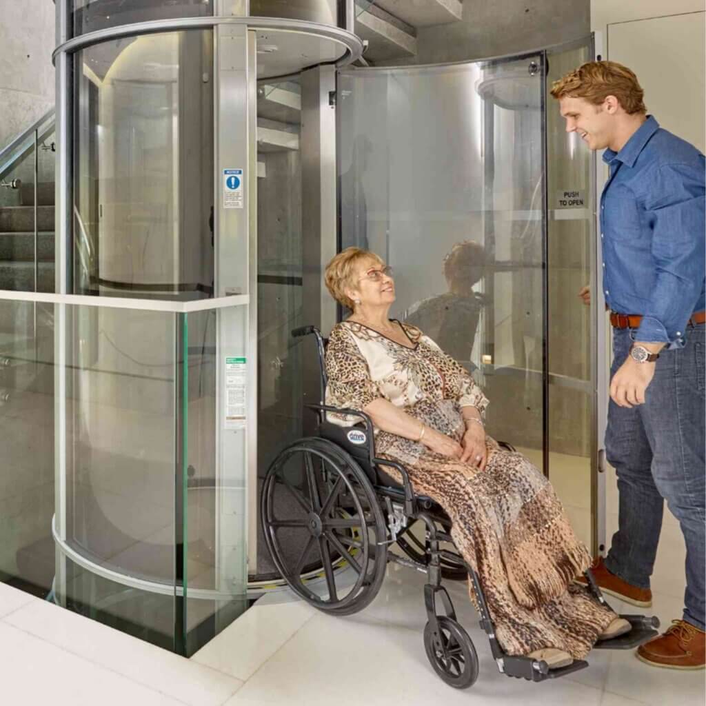Donna in carrozzina che sta usando un miniascensore con l'accompagnatore
