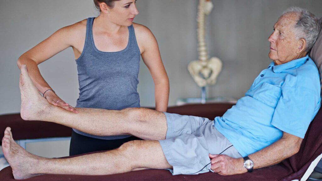 Anziano durante una sessione di fisioterapia con terapista professionista