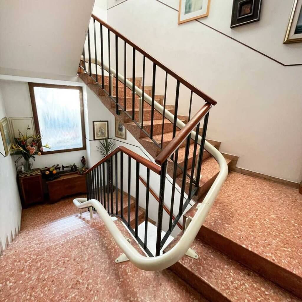 Montascale a poltroncina su guida curva installato in scala interna per abbattere le barriere architettoniche.