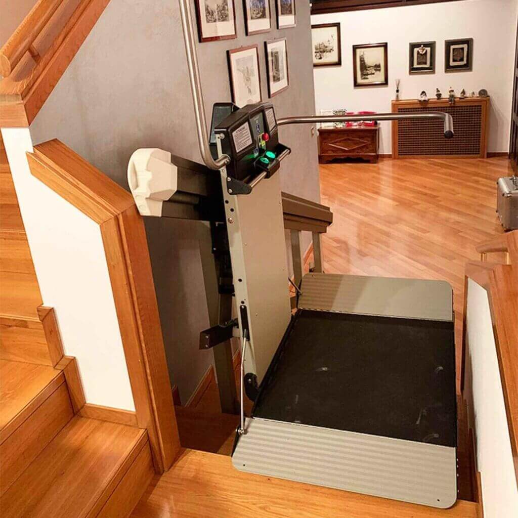 Un servoscala a piattaforma fermo ai piedi di una scala all'interno di un'abitazione