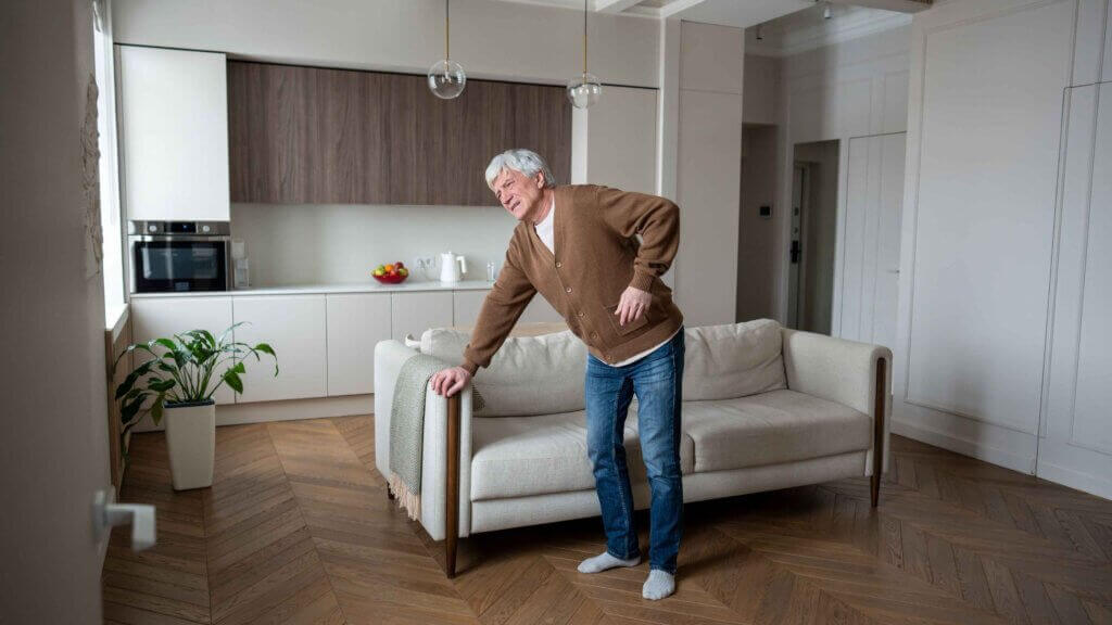 Uomo anziano con difficoltà ad alzarsi dal divano
